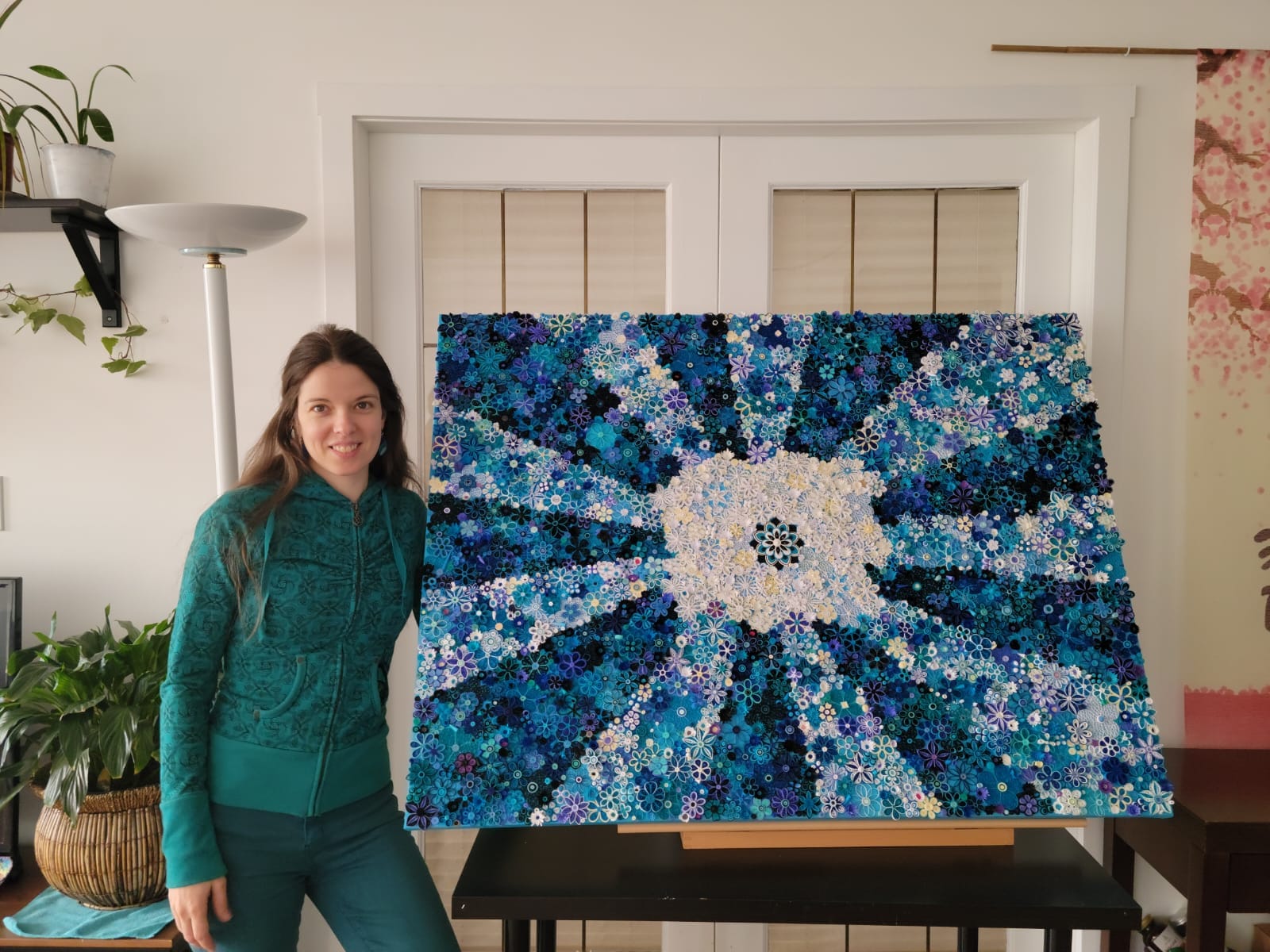 Martha Villa Martin standing beside her blue quilled paper artwork Éclat Bleu